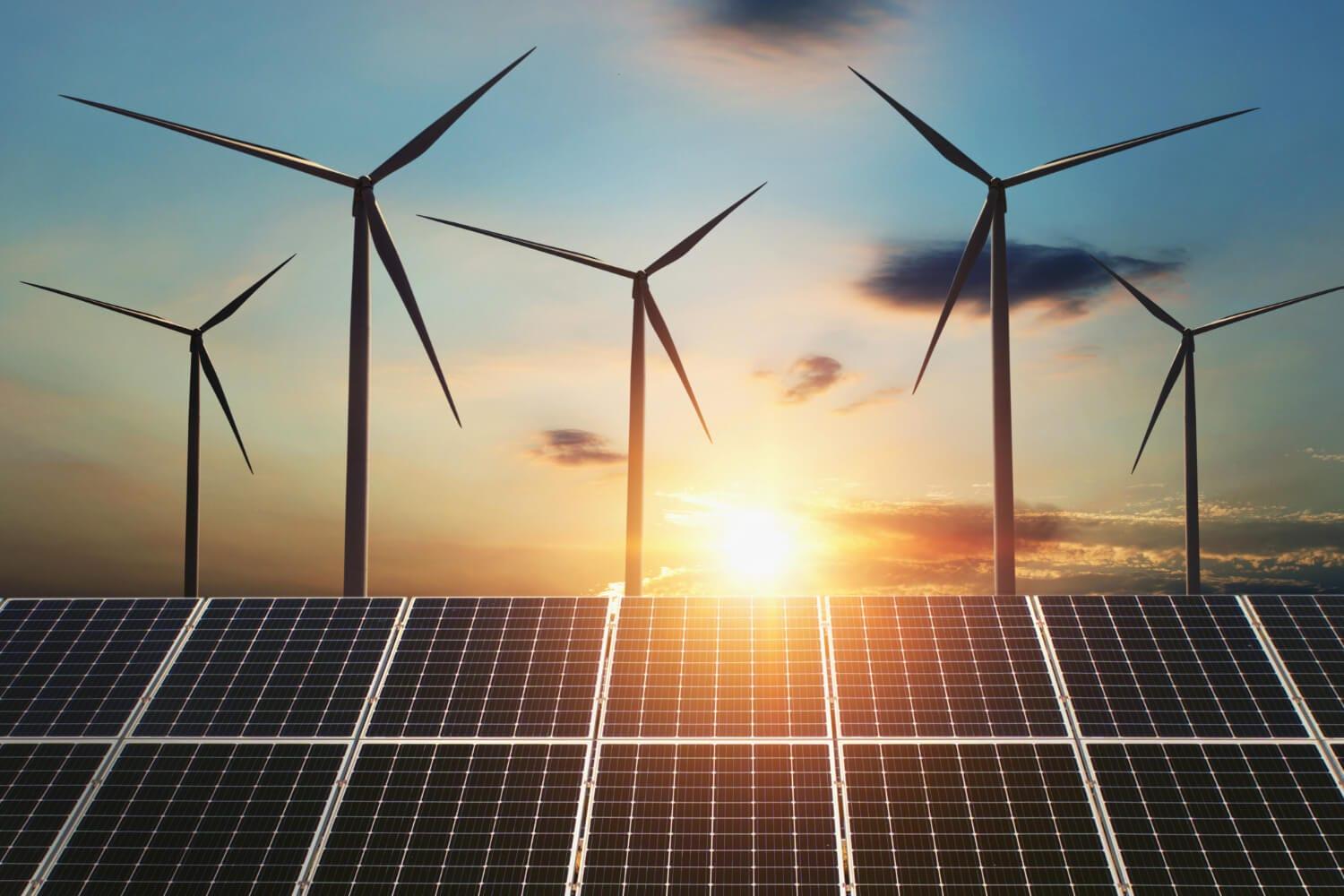 Wind turbines and solar panels at sunrise